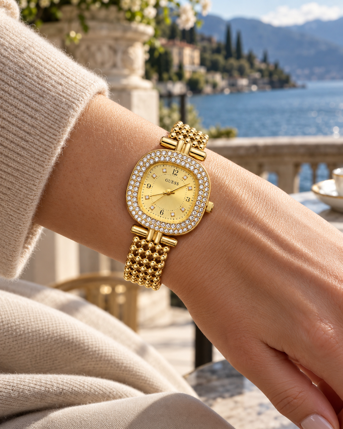 Guess women's watch on wrist Lebanon - gold-tone cushion case with double crystal bezel, champagne sunray dial with crystal markers, beaded gold ball-chain bracelet